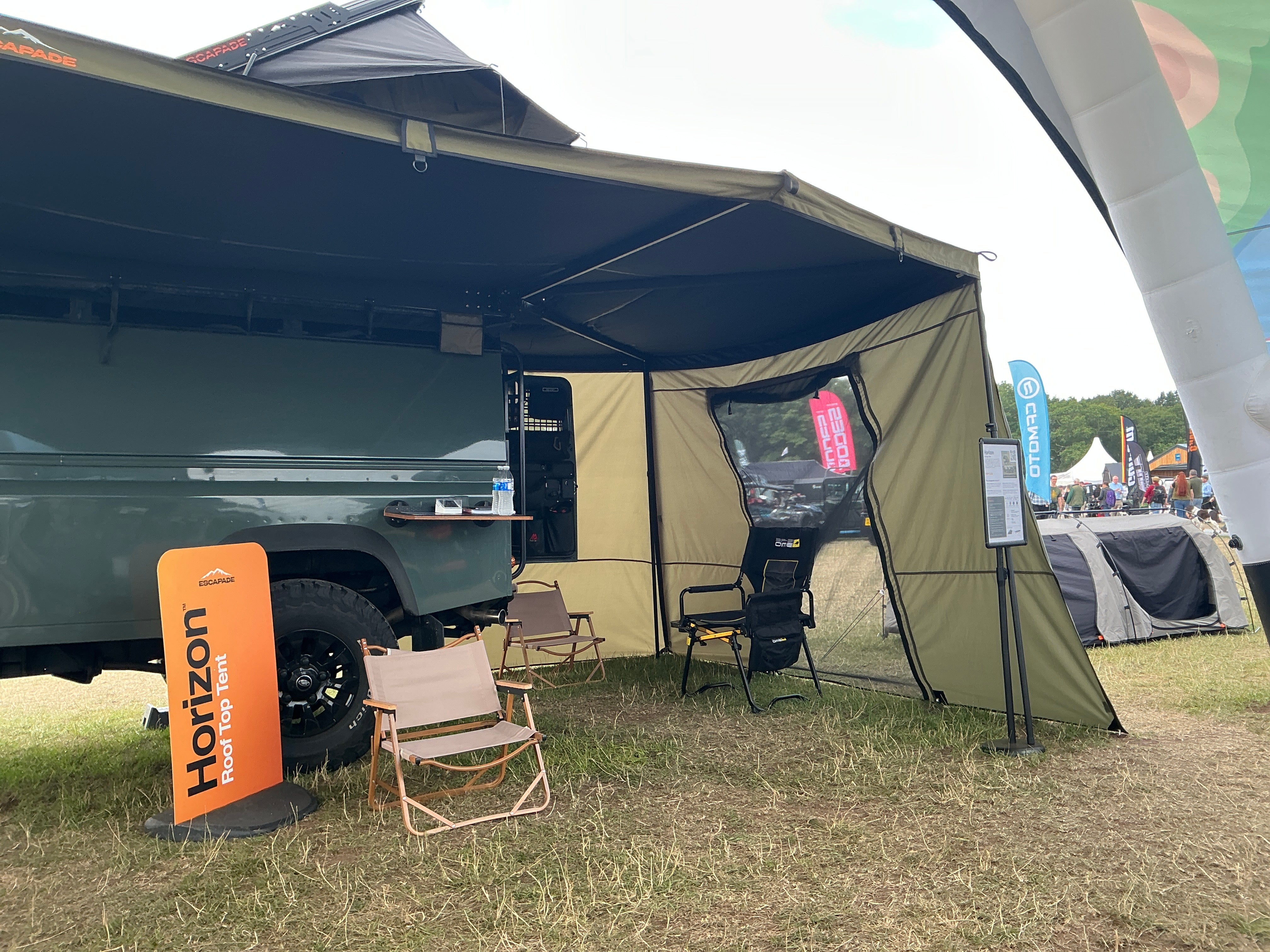 Outdoor setup with a tent, chairs, and a Horizon brand sign on a grassy area.